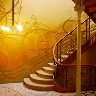Escalier intérieur Art Nouveau avec ferronnerie aux lignes courbes et décor végétal, caractéristique des architectures du début du XXᵉ siècle.