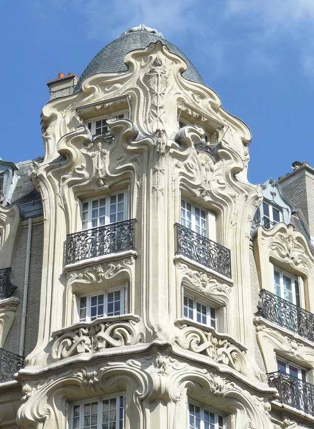 Façade d’immeuble Art Nouveau avec décor sculpté végétal et balcons en ferronnerie courbe, caractéristique de l’architecture du début du XXᵉ siècle.
