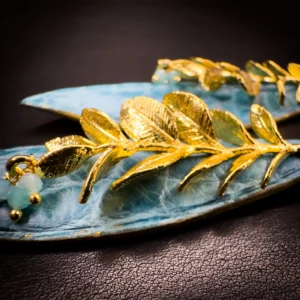 Détail du rameau végétal doré à l'or fin 24 carats, des perles d'amazonite céladon et du cuir d'alligator bleu