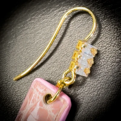 Détail d'une boucle d'oreille en alligator rose brillant et zirconiums