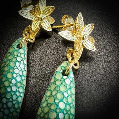 Détail de boucles d'oreilles en galuchat vert céladon avec fleur dorée à l'or fin 24 carats