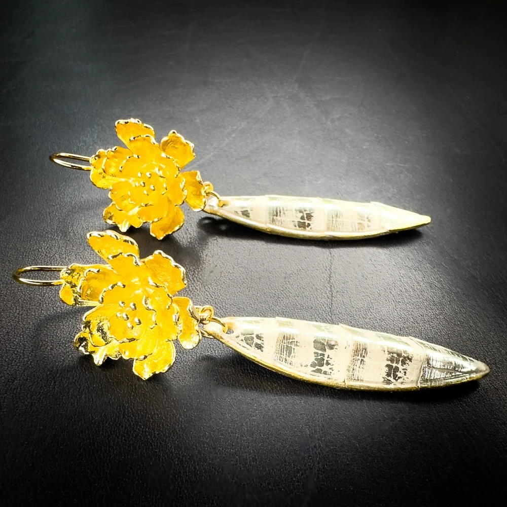 Boucles d'oreilles artisanales en python couleur sable rehaussé de touches or et montées sur laiton doré à l'or fin 24 carats. Boucles d'oreilles artisanales en python couleur sable rehaussé de touches or et montées sur laiton doré à l'or fin 24 carats.